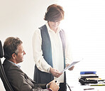 Two colleagues talking finance in a modern office. A mature businessman and businesswoman working with paperwork, discussing business matters