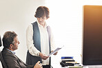 Two colleagues talking finance in a modern office. A mature businessman and businesswoman working with paperwork, discussing business matters