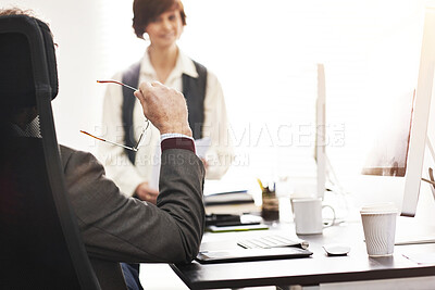 Buy stock photo Two colleagues talking in a modern office. A mature businessman and businesswoman working together and having a meeting, discussing business matters