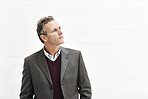 A businessman thinking, isolated on a white background. A mature male executive looking thoughtful, planning business moves in an office or studio