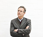 A businessman thinking, isolated on a white background. A mature male executive looking thoughtful, planning business moves in an office or studio