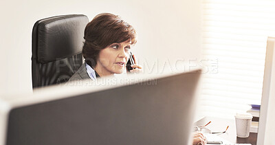 Buy stock photo A businesswoman using a phone to make a call in a modern office. A mature female executive talking on her smartphone browsing online with a computer for business