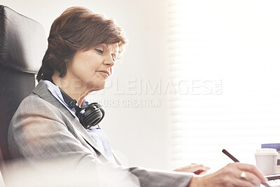 Buy stock photo A businesswoman writing a note in a modern office. A mature female executive working with paperwork for business at her desk