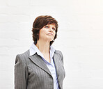 A businesswoman thinking, isolated on a white background. A mature female executive looking thoughtful, planning business moves in an office or studio