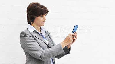 Buy stock photo A businesswoman using a phone, isolated on a white background. A mature female executive browsing online for business with her smartphone in an office or studio
