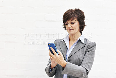 Buy stock photo A businesswoman using a phone, isolated on a white background. A mature female executive browsing online for business with her smartphone in an office or studio