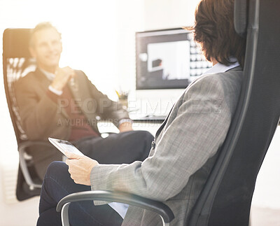 Buy stock photo Two colleagues using a tablet in a modern office. A mature businessman and businesswoman working online with a touchscreen, talking about business matters