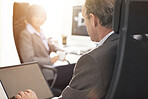 Two colleagues using a laptop in a modern office. A mature businessman and businesswoman working online with a computer, talking about business matters