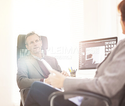 Buy stock photo Two colleagues using a tablet in a modern office. A mature businessman and businesswoman working online with a touchscreen, talking about business matters