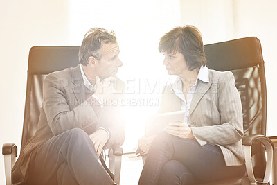 Buy stock photo Two colleagues using a tablet in a modern office. A mature businessman and businesswoman working online with a touchscreen, talking about business matters