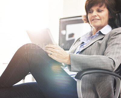 Buy stock photo A businesswoman using a digital tablet in a modern office. A mature female executive browsing online for business with a touchscreen at work
