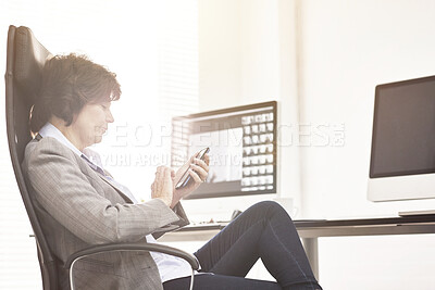 Buy stock photo A businesswoman using a phone in a modern office. A mature female executive browsing online for business with her smartphone at work