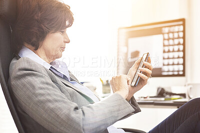Buy stock photo A businesswoman using a phone in a modern office. A mature female executive browsing online for business with her smartphone at work