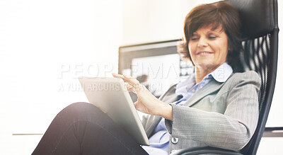 Buy stock photo A businesswoman using a digital tablet in a modern office. A mature female executive browsing online for business with a touchscreen at work