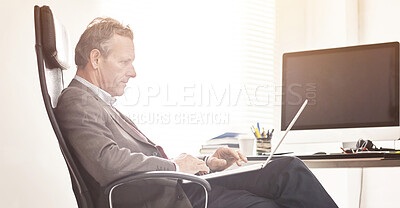 Buy stock photo A businessman using a laptop in a modern office. A mature male executive browsing online for business with a computer at work