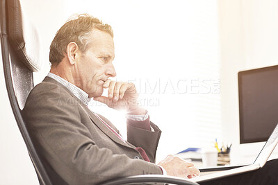 Buy stock photo A businessman using a laptop in a modern office. A mature male executive browsing online for business with a computer at work