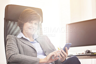 Buy stock photo A businesswoman using a phone in a modern office. A mature female executive browsing online for business with her smartphone at work