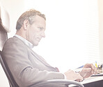 A businessman using a laptop in a modern office. A mature male executive browsing online for business with a computer at work