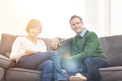 Buy stock photo A mature couple relaxing at home. Portrait of a happy senior man and woman having a coffee or tea break, sharing a cosy moment on the couch