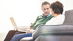 A mature couple using a laptop, relaxing at home. A happy senior man and woman in love browsing online with a computer on the couch