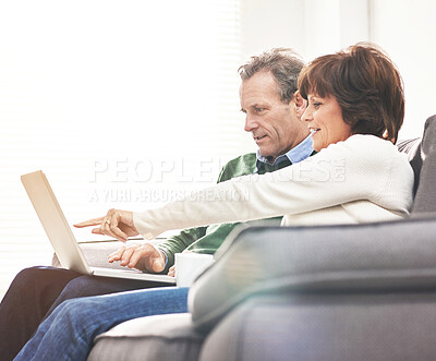 Buy stock photo A mature couple using a laptop, relaxing at home. A happy senior man and woman in love browsing online with a computer on the couch