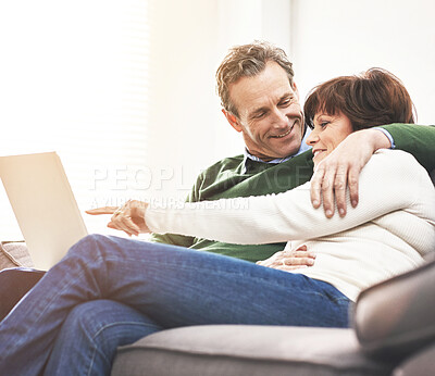 Buy stock photo A mature couple using a laptop, relaxing at home. A happy senior man and woman in love browsing online with a computer on the couch