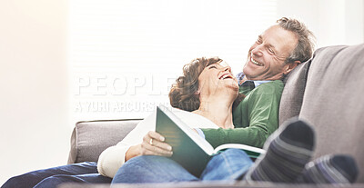 Buy stock photo A mature couple reading a book and relaxing at home. A happy senior man and woman in love sharing a happy and comfortable moment on the couch