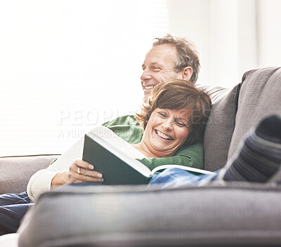 Buy stock photo A mature couple reading a book and relaxing at home. A happy senior man and woman in love sharing a happy and comfortable moment on the couch