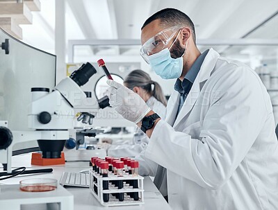 Buy stock photo Scientist doing research for covid using a microscope and test tube in a lab. Healthcare worker in biotechnology, medicine and analytics testing liquid in science laboratory for blood sample results