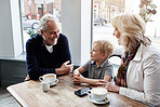 Happy family, grandparents and child at cafe for conversation, talking of holiday and visit in London. Senior people with boy or kid at coffee shop for discussion, funny chat and planning at table