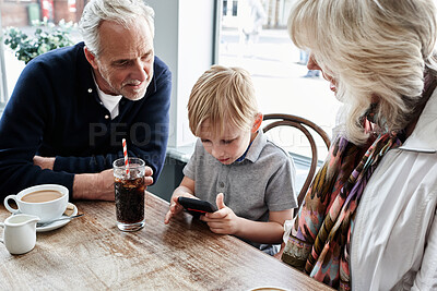 Buy stock photo Family, grandparents and kid with phone at cafe for online games, e learning and streaming video together. Senior people with boy child at coffee shop and mobile for chat or reading restaurant menu