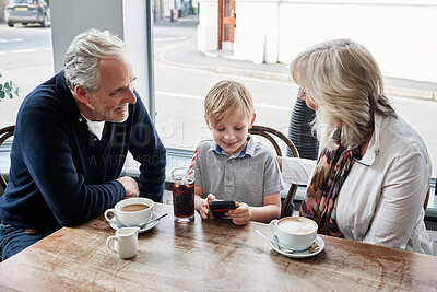 Buy stock photo Family, kid and cafe with phone, video or click with smile for soda, relax or streaming on app. Grandparents, family and child with tea cup, coffee shop and smartphone with reading, press and cartoon