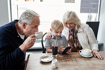 Buy stock photo Family, kid and cafe with phone, games and click with smile for soda, relax and watch video. Grandparents, typing and child with tea cup, coffee shop and smartphone with reading, press and cartoon