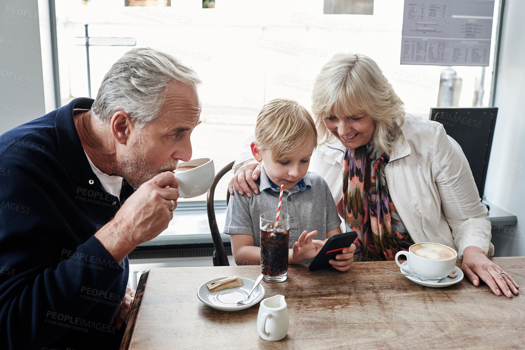 Buy stock photo Family, kid and cafe with phone, games and click with smile for soda, relax and watch video. Grandparents, typing and child with tea cup, coffee shop and smartphone with reading, press and cartoon
