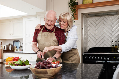 Buy stock photo Happy, hug and senior couple cooking in a kitchen with care, conversation and support at home. Health, food and old people with love in a house for brunch, salad or meal prep with raw vegetables