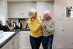 Senior couple, singing and kitchen with spoon for celebration, comic game or memory with love in home. Elderly woman, old man and toy microphone for karaoke, performance and party in happy retirement