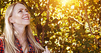 Sunshine, happy and woman by trees in morning for wellness, fresh air and relax outdoors. Countryside, smile and person in forest, woods and nature for calm, joy and freedom in natural environment