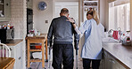 Nurse support senior man in crutches in home kitchen, medical rehabilitation and recovery. Caregiver back, person with a disability walk and help, health and physiotherapy, healing injury or accident