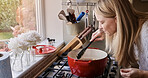 Woman, cooking and smell pot in kitchen, home or smile for healthy ingredients, meal prep or nutrition. Chef person, stove and food with spoon, thinking and process for diet, lunch or dinner in house