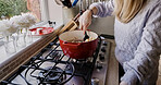 Woman, stove and hand or spoon cooking for stew meal, warm dinner or fresh soup. Female person, gas appliance and prepare vegetable nutrition eating for pot food or taste recipe, love dish for health