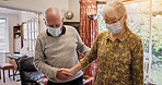 Senior couple, support and face mask in home, holding hands and together with love in living room. Covid, safety or old people helping and care for health in corona pandemic with trust and protection