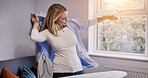 Woman, wear clothes and ironing in home, laundry and housework in living room, apartment or house. Housekeeping service, chores and person with fresh shirt, maid cleaning or domestic work for hygiene