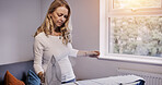Woman iron fabric on board in house, laundry and housework chores in living room, apartment or home Housekeeping service, electrical appliance and clothes, maid cleaning and domestic work for hygiene