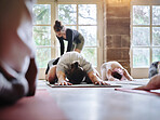 Stretching, woman and teaching yoga to group of people on floor for fitness class, health and mindfulness together. Help, showus or helping, men and women in exercise on ground, body wellness and gym