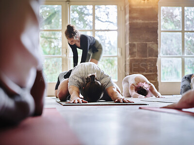 Buy stock photo Stretching, woman and teaching yoga to group of people on floor for fitness class, health and mindfulness together. Help, peace or helping, men and women in exercise on ground, body wellness and gym