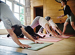 Yoga, downward dog and coach stretching in class at the gym, pilates exercise and fitness. Group, instructor and down facing pose for healthy body, wellness and lesson in club with people on floor