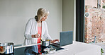 Cooking, kitchen and senior woman with computer for online recipe for lunch, supper and dinner in home. Retirement, food website and person on laptop with ingredients, vegetables and prepare meal