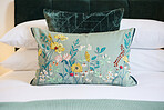 Bedroom interior, pillow and hotel with hospitality, accommodation for comfort with furniture and decor. Room, property or house for vacation, getaway or luxury resort with closeup of floral design