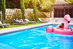 Man, relax and swimming pool on float outdoor for inflatable flamingo, love and enjoy water on vacation resort. Smile, couple and floating for romance, poolside and bonding on summer holiday at villa