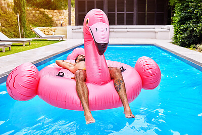 Buy stock photo Man, outdoor and relax on inflatable in swimming pool for summer vacation, weekend break or getaway at resort. Holiday, water and male person on flamingo float for sunbathing, comfortable or peace